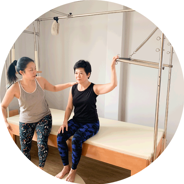 An image of the trapeze table: a large flat table with a steel structure over that allows you to do a range of clinical pilates exercises.
